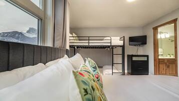 A bedroom with a bunk bed, a bedside table, a TV, and a wooden wardrobe.