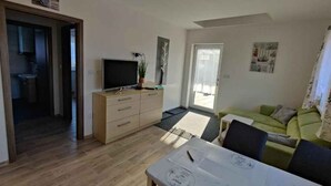 A modern living room with a dining table, a sofa, and a television.