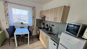 A compact kitchen with a dining table, chairs, a sink, a stove, and a refrigerator.