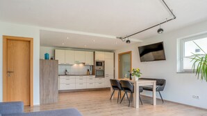 A modern apartment with a dining area, kitchen, and living space.