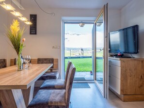 A modern dining area with a wooden table, chairs, and a vase with flowers. - Apartment Josef by Interhome (Fügen)
