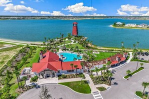 An aerial view of a resort with a central building, a swimming pool, and a tower.