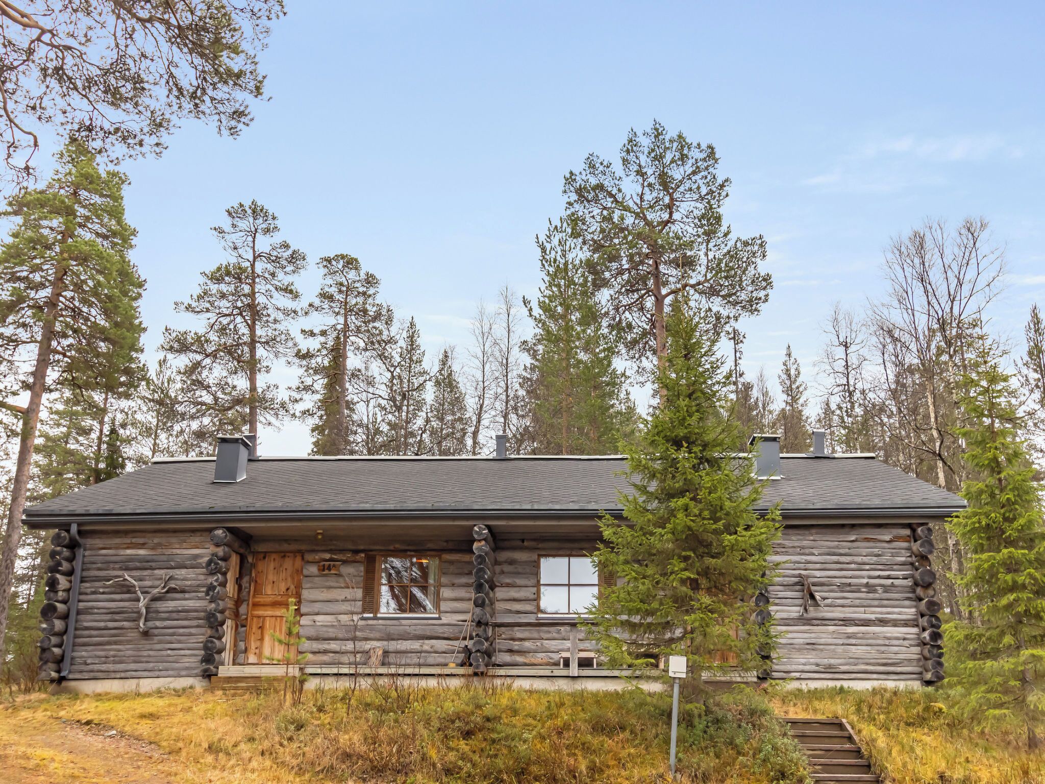 A log cabin with a wooden door, a window, and a chimney.