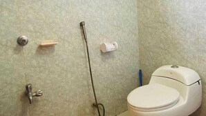 A bathroom with a toilet, a shower, a red bucket, and a window. - Heaven beach Resort Saint Martin (Saint Martin's Island)