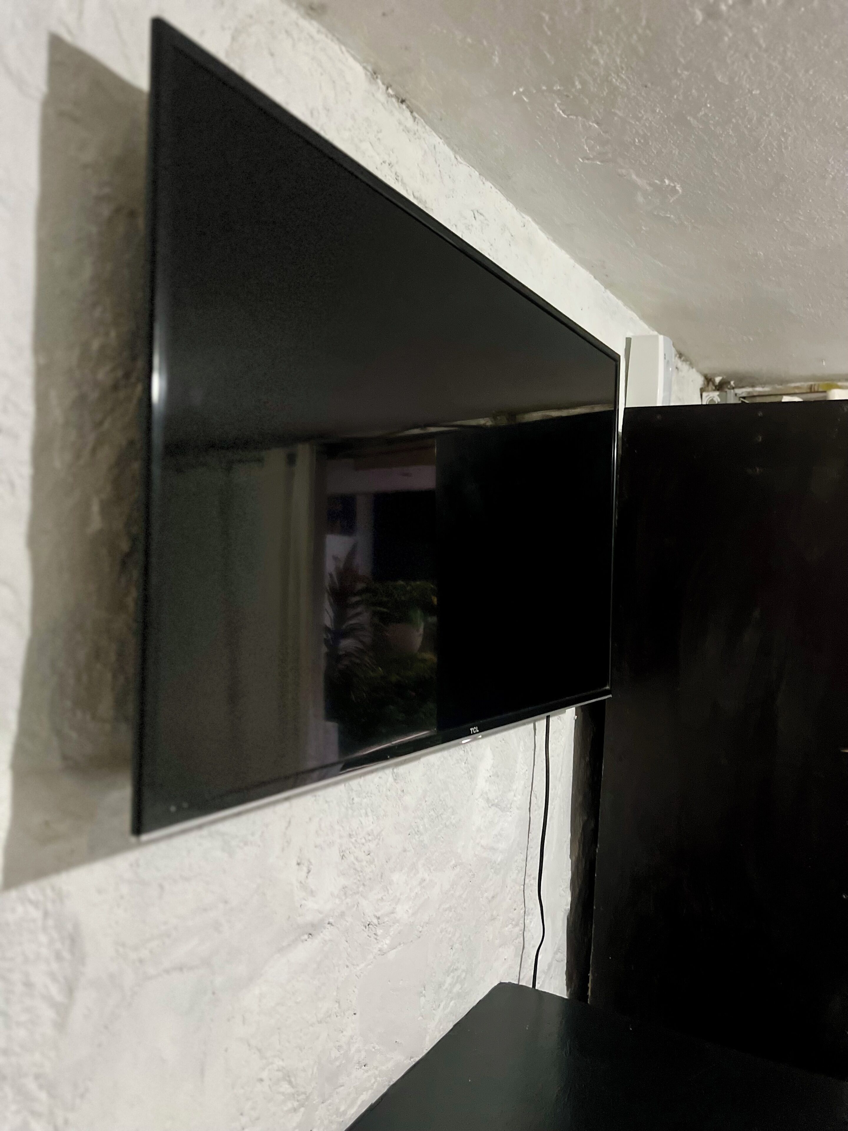 Un téléviseur à écran plat fixé sur un mur blanc à texture.