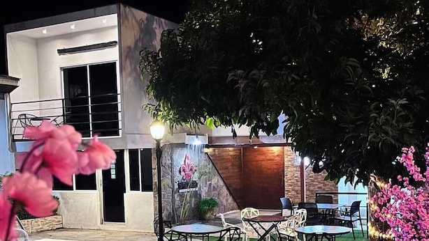 A modern outdoor patio with a pool, dining area, and a waterfall feature. - Hotel Villa Napoli (Santa Ana)