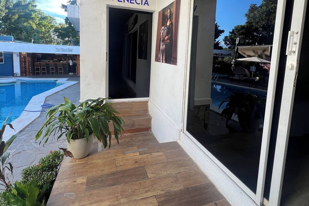 A hotel entrance with a pool area visible through the glass doors.