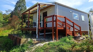 Ein kleines, eingeschossiges Haus mit einer Holzterrasse und einer überdachten Veranda.