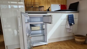 Eine Küche mit Kühlschrank, Schneidebrett und Korb.