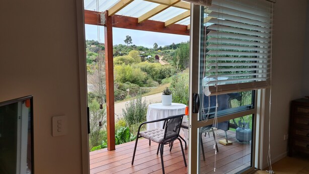 Ein Zimmer mit einer großen Schiebeglasdoor, die auf eine Terrasse mit Tisch und Stühlen führt. Es gibt einen Fernseher auf einem Schrank und eine Steckdose am Boden.