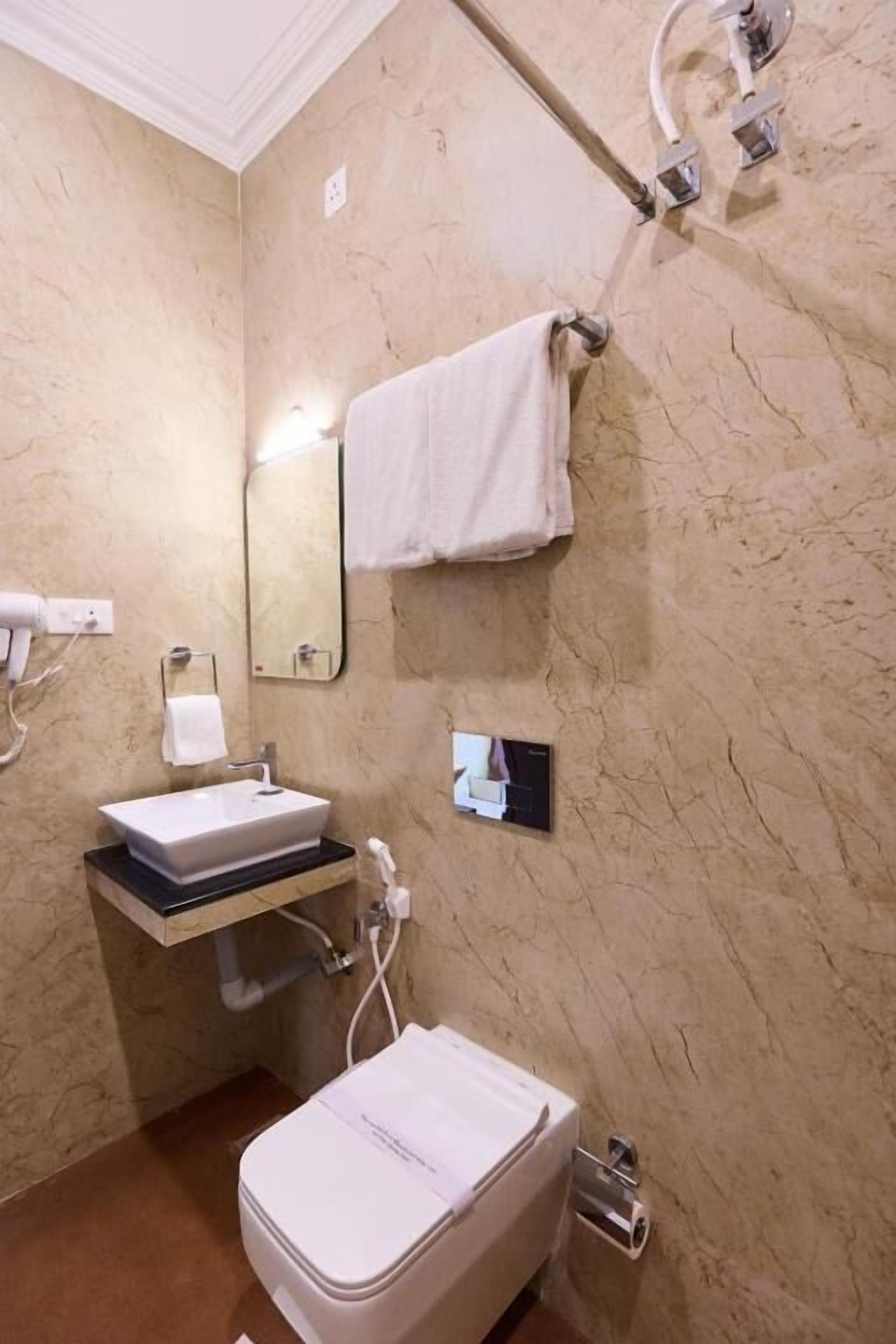 A bathroom with a white sink, a mirror, a towel rack, and a toilet.