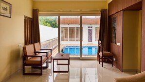 Un balcon spacieux avec une piscine, aménagé avec deux chaises et une petite table, et une porte-fenêtre coulissante donnant sur un espace extérieur abrité.