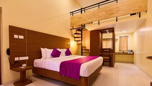 Une chambre d’hôtel moderne avec un lit en bois, un bureau et un petit coin salon.