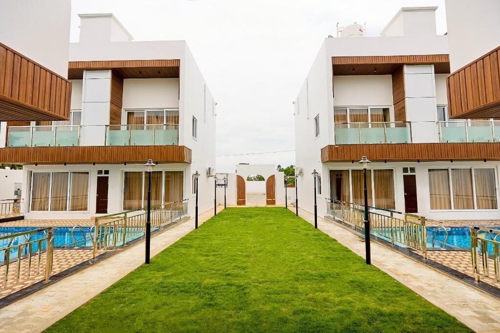 Un hotel moderno con un patio central, piscina y edificios de dos pisos con balcones.