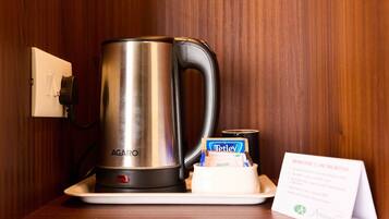 A stainless steel AGARO coffee maker on a white tray, a Tetley tea box, and a sign with instructions.