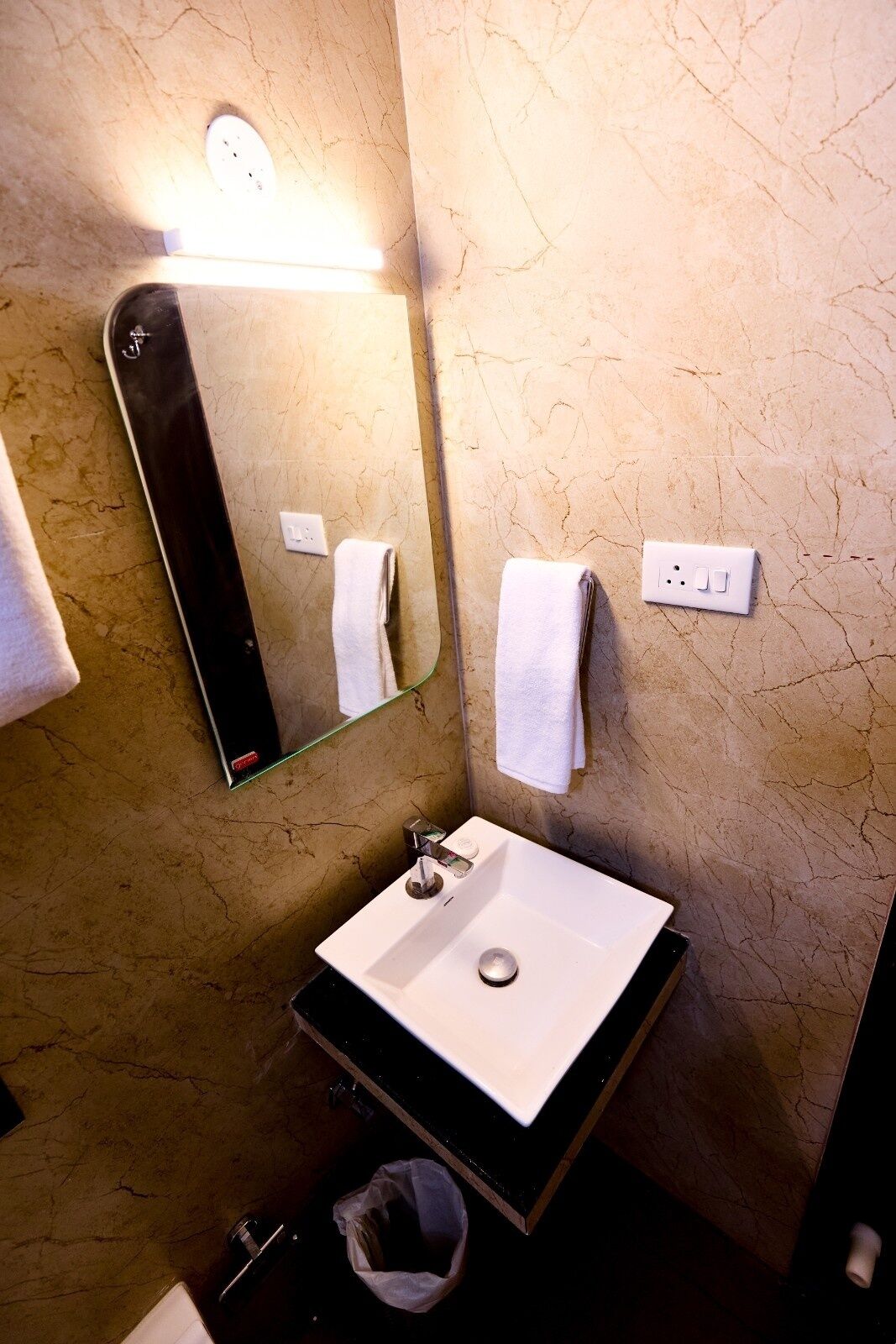 A bathroom with a white sink, a mirror, and two white towels hanging on the wall.