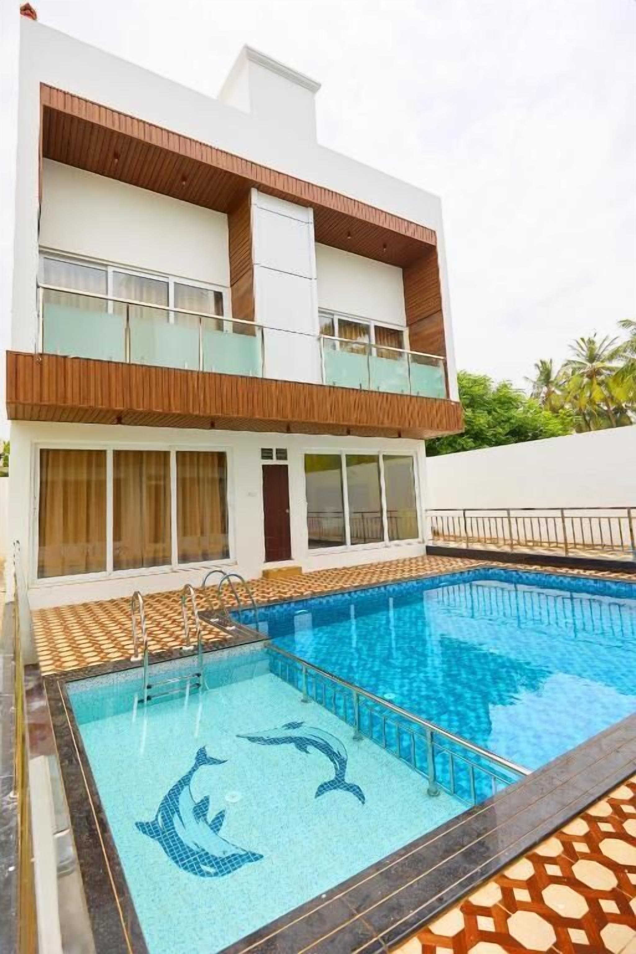 Un bâtiment à deux étages doté d’une piscine dont le carrelage représente des dauphins.