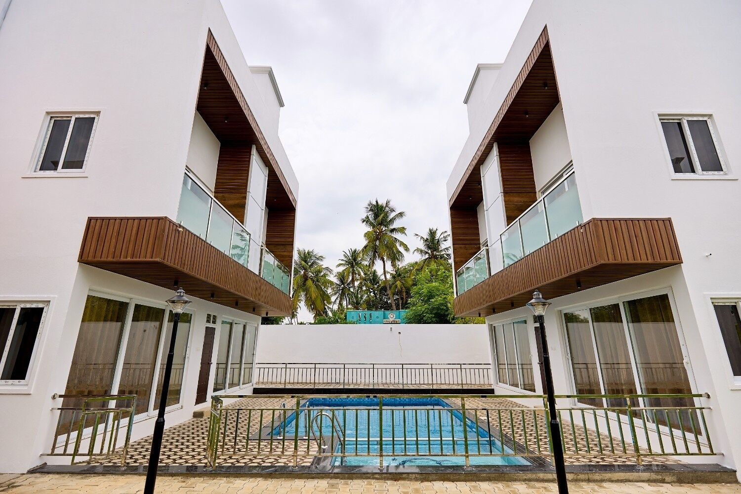 A modern building with a central pool, two-story balconies, and a view of palm trees.