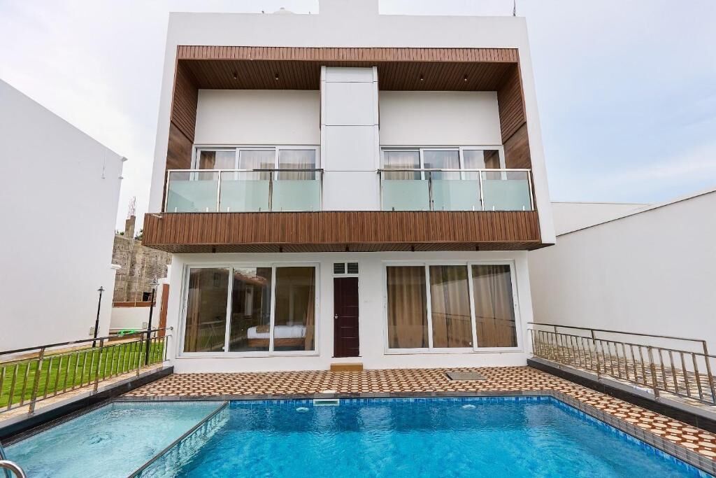 A modern two-story house with a swimming pool in front.