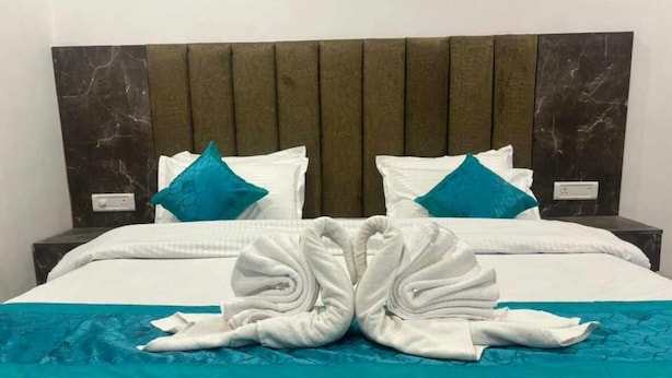 Une chambre d’hôtel avec un lit, deux tables de chevet, une tête de lit en marbre et une couvre-lit de couleur turquoise.