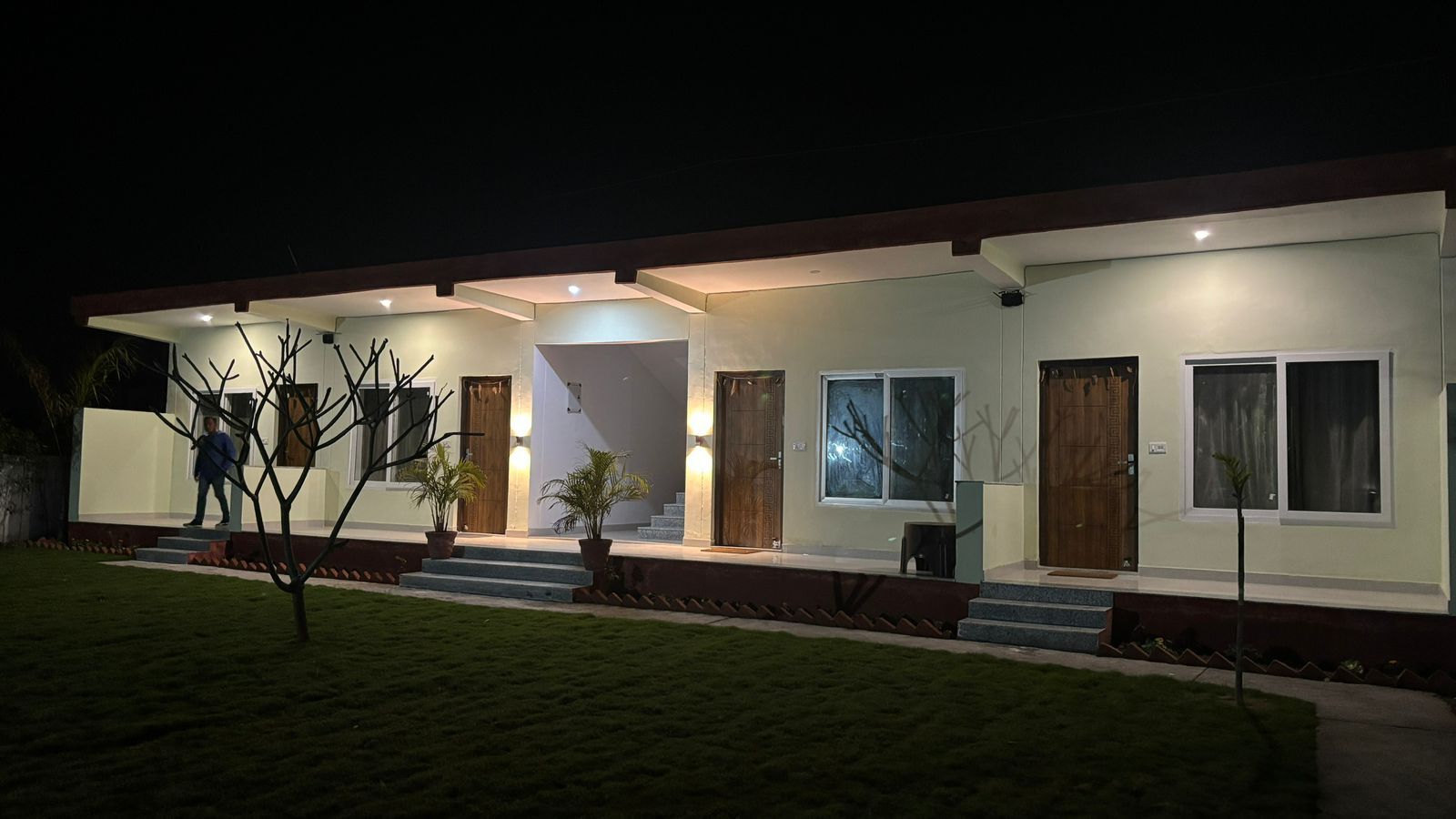 A modern house with a covered porch, multiple doors, and a well-lit entrance.