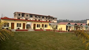 A building with multiple floors, a central staircase, and a surrounding lawn. - Rajaji Retreat Resort (Ganga Bhogpur Talla)