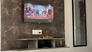 Un téléviseur fixé à un mur de marbre, avec une étagère en dessous.