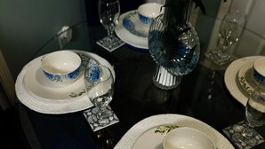 Ein Esstisch, gedeckt mit weißen Tellern, blauen Blumenmustern und klaren Gläsern.