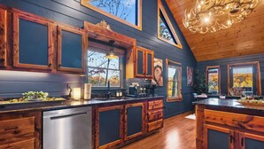 A modern kitchen with wooden cabinets, a stainless steel dishwasher, and a large island. - The Elk's Club - Views, Firepit, Hot Tub, Pickle Ball & Game Rm (Blue Ridge)