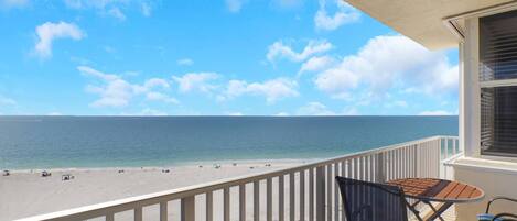 A balcony with a view of a beach and ocean.