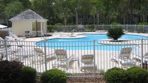 A swimming pool with lounge chairs, a small gazebo, and a fenced area with trees in the background. - Family friendly 3-bedroom townhome with large sunroom  in St. Simons Island (St. Simons Island)