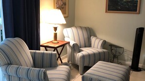 A living room with striped armchairs, a small table with a lamp, a painting on the wall, and a floor lamp. - Family friendly 3-bedroom townhome with large sunroom  in St. Simons Island (St. Simons Island)