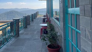 A balcony with a view of mountains, a potted plant, and outdoor seating. - Kasar Escape (Almora)