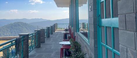 A balcony with a view of mountains, a potted plant, and outdoor seating.