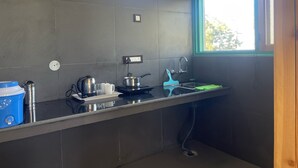 A compact kitchen with a gas stove, a sink, and a window providing natural light. - Kasar Escape (Almora)