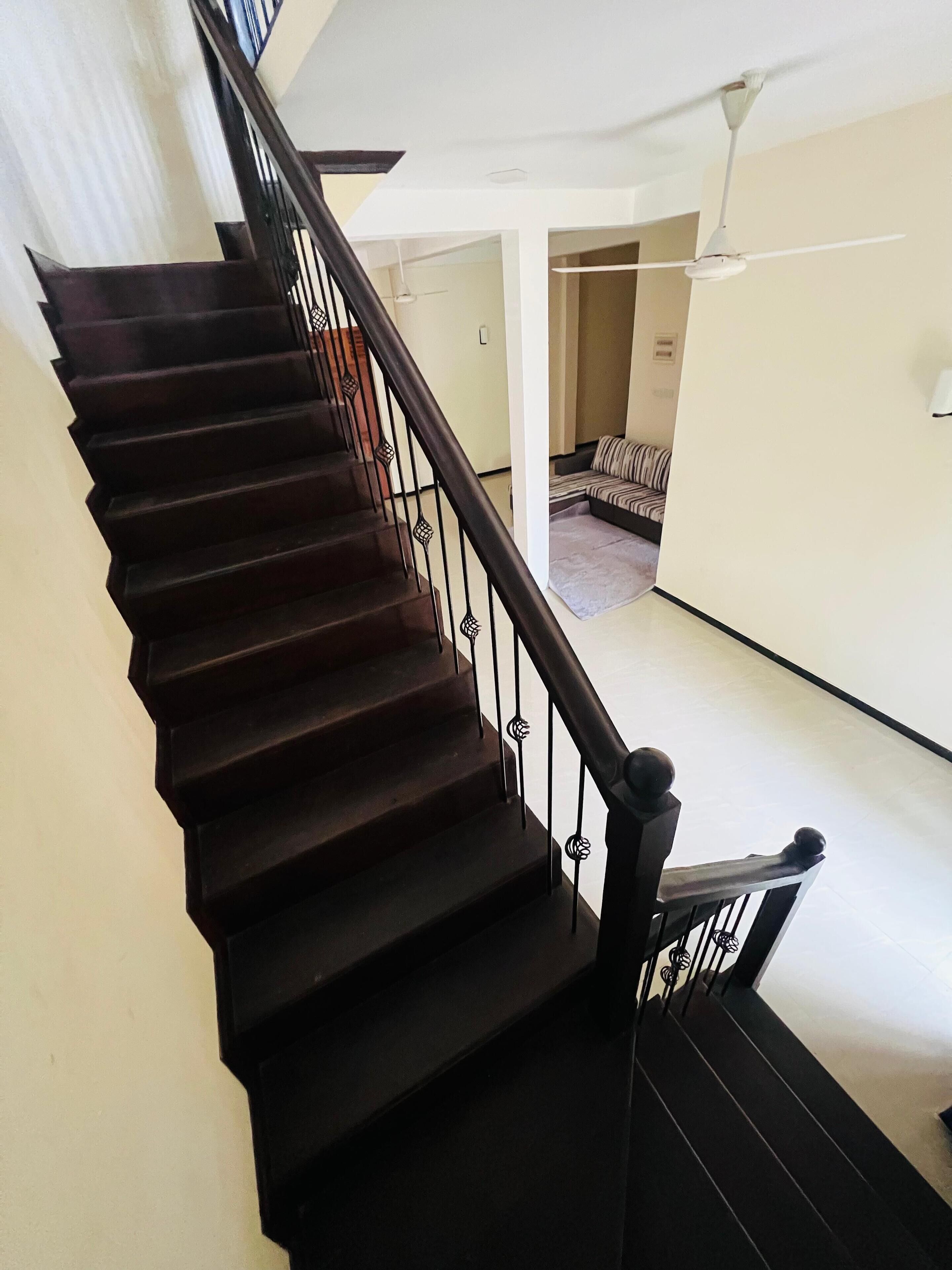 A staircase with dark wooden steps and black metal railings.