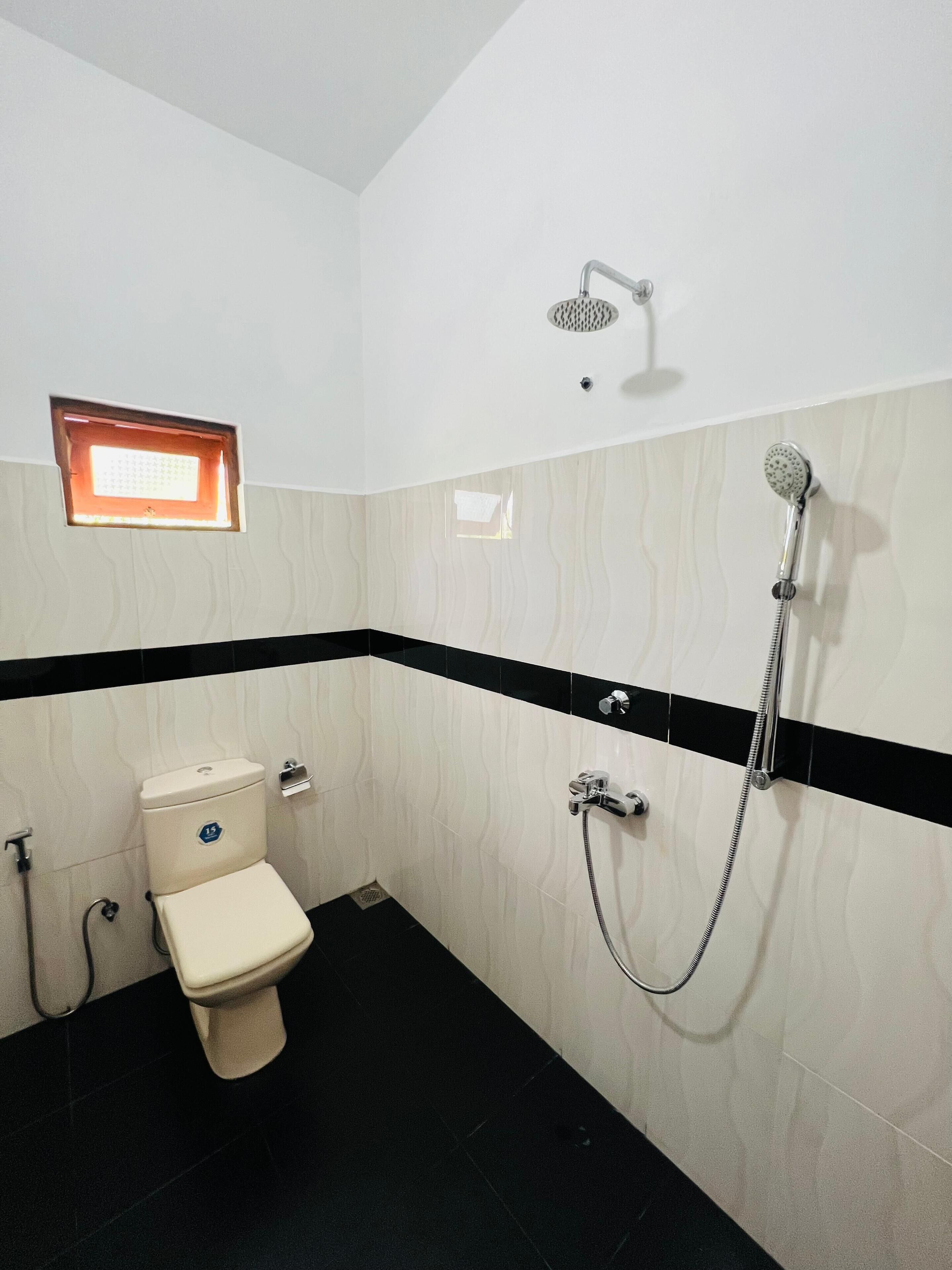 A bathroom with a toilet, a shower, and a small window.