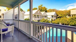 A covered balcony with a pool, white-framed windows, and a view of other houses. - Life Is A Breeze | Pool, Parking & Walk to Duval in Old Town Key West (Key West)