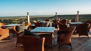 An outdoor seating area with wicker furniture and tables, overlooking a scenic landscape. - Papumpare Jungle Resort (Papumpare)
