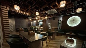 A modern interior with a central bar area, wooden flooring, and a unique circular light fixture on the wall. - Papumpare Jungle Resort (Papumpare)