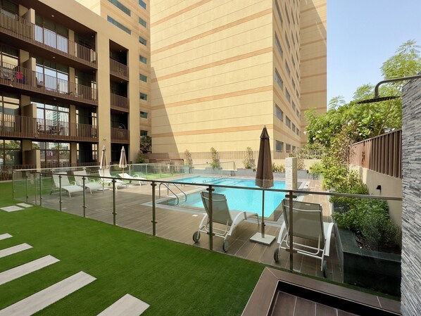 Un hôtel moderne doté d’une piscine sur le toit, d’une pelouse verdoyante et de nombreux balcons.