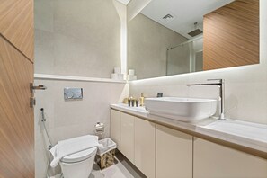 Une salle de bain moderne avec un grand lavabo blanc, des toilettes et une douche.