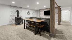 A modern interior with a stone wall, a wooden table, a bench, a fireplace, and a gray sofa. - East Farmington Hideaway (Farmington)