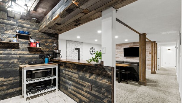 A modern kitchen with a wooden accent wall, a built-in microwave, and a coffee station. - East Farmington Hideaway (Farmington)