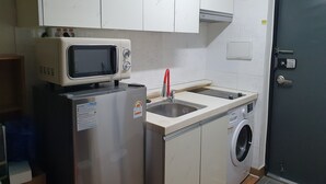 A compact kitchen with a microwave, sink, and washing machine.