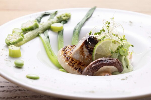 A plate with grilled meat, asparagus, and a lime wedge.