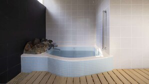 Un baño moderno con bañera en esquina, paredes de azulejos y piso de madera.