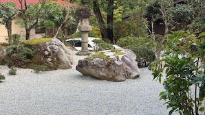 Un jardín japonés tradicional con un sendero de grava, rocas grandes y un farol de piedra.