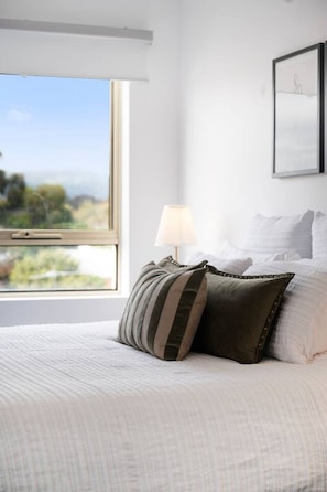 A bedroom with a large window, a bed with white bedding, and a lamp. - Adelaide `Hills-View` Retreat (Adelaide)