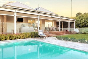 A modern house with a swimming pool, outdoor seating, and a covered patio area. - The Retreat on Chaffey (Mildura)